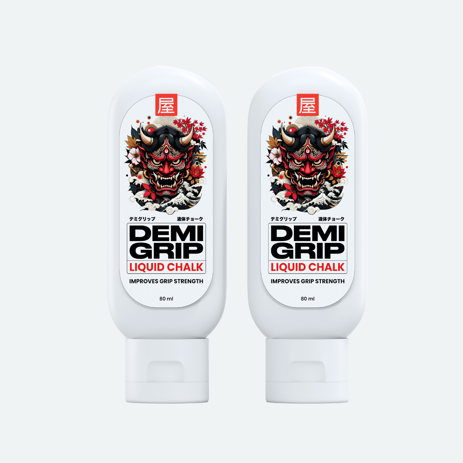 Two bottles of Demi Grip Liquid Chalk, each featuring a bold and striking label with a traditional Japanese Oni (demon) mask design. The product name 'DEMI GRIP' is prominently displayed in black text, with 'LIQUID CHALK' written below in red. The label also includes the phrase 'IMPROVES GRIP STRENGTH' and indicates a 60 ml capacity. The bottles are white with a sleek, modern design, emphasizing functionality and cultural aesthetics.