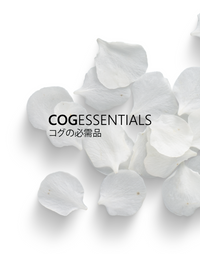 A minimalist design featuring scattered white flower petals on a clean background. The text 'COGEssentials' is prominently displayed in bold, with Japanese characters ('コグの必需品') underneath, translating to 'Cog's Essentials.' The overall aesthetic conveys purity and simplicity.